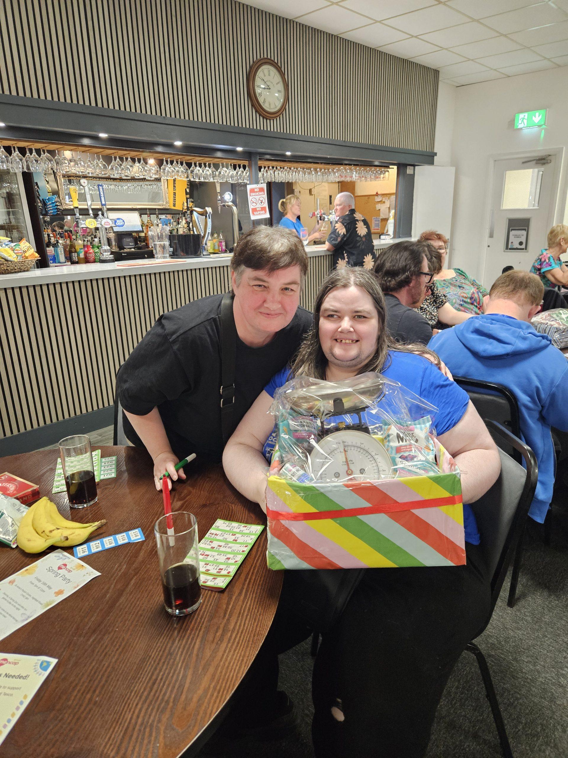 Two people smiling for a photo with their bingo prize.